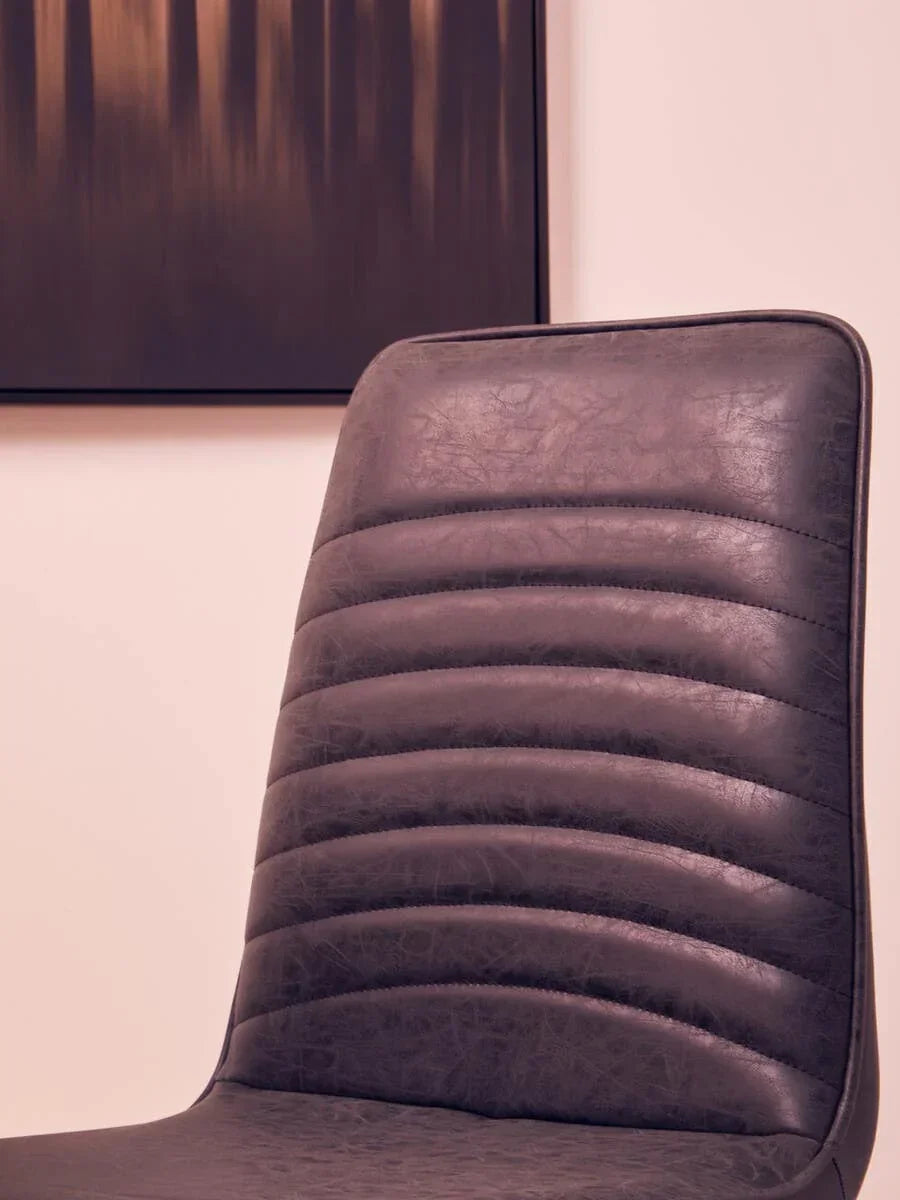 Closeup of dark faux leather dining chair with horizontal stitched detail