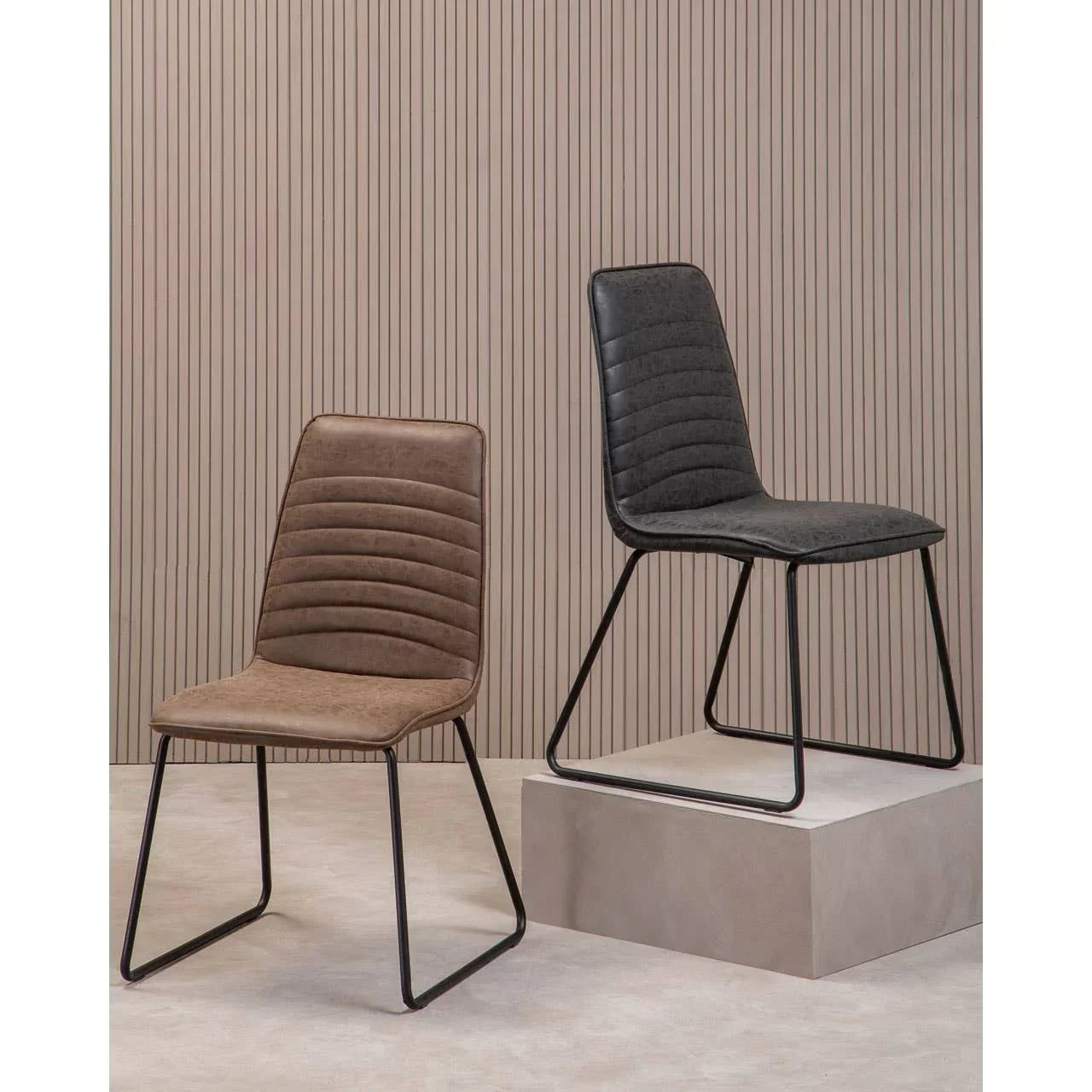 Set of two dining chairs with black metal legs, one grey and one brown, in modern setting