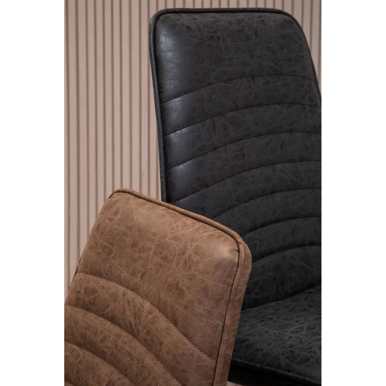 Detail of brown and black faux leather dining chairs with stitched upholstery