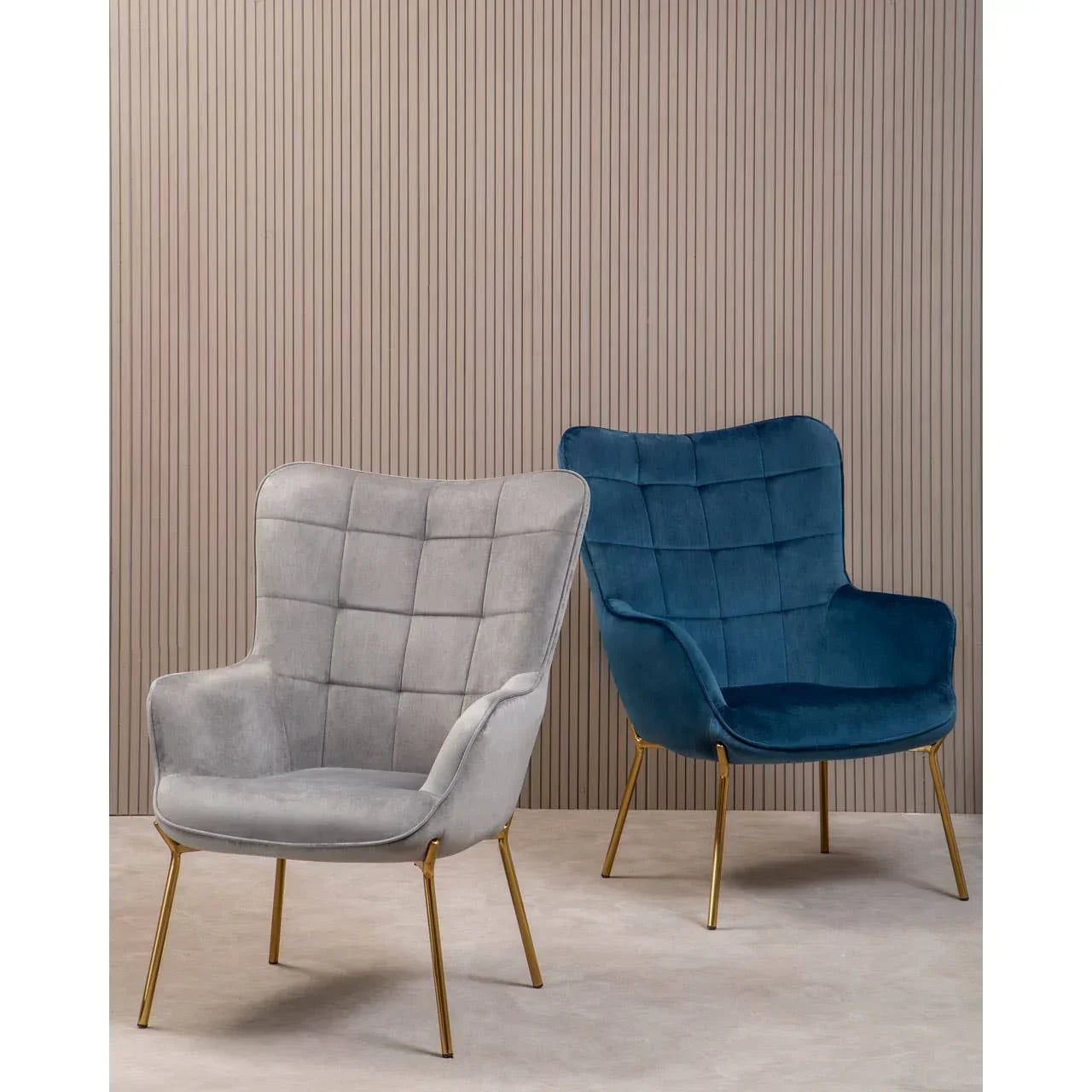 Grey and blue velvet accent chairs with gold legs against a beige ribbed wall