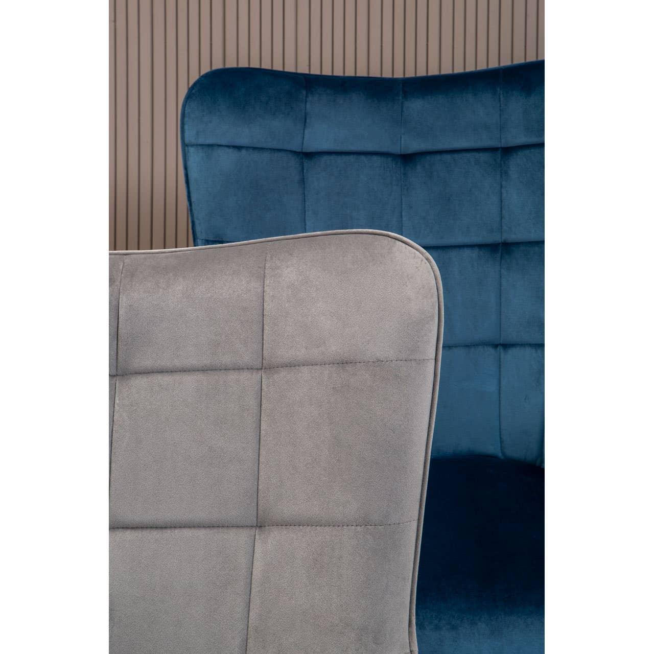 Grey fabric chair in front of blue velvet accent chair with stitched square pattern