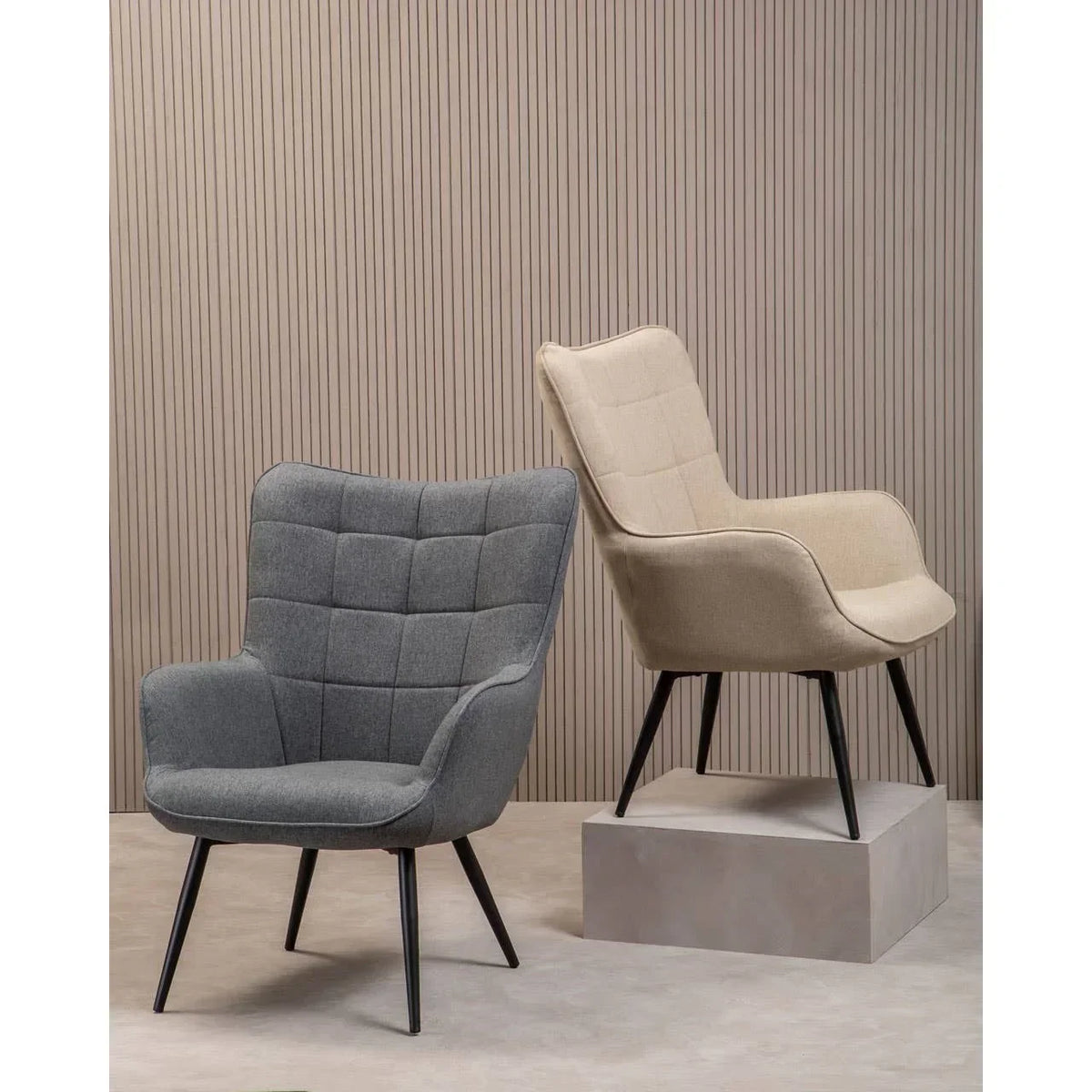 Grey and beige fabric accent chairs with black legs against textured wall
