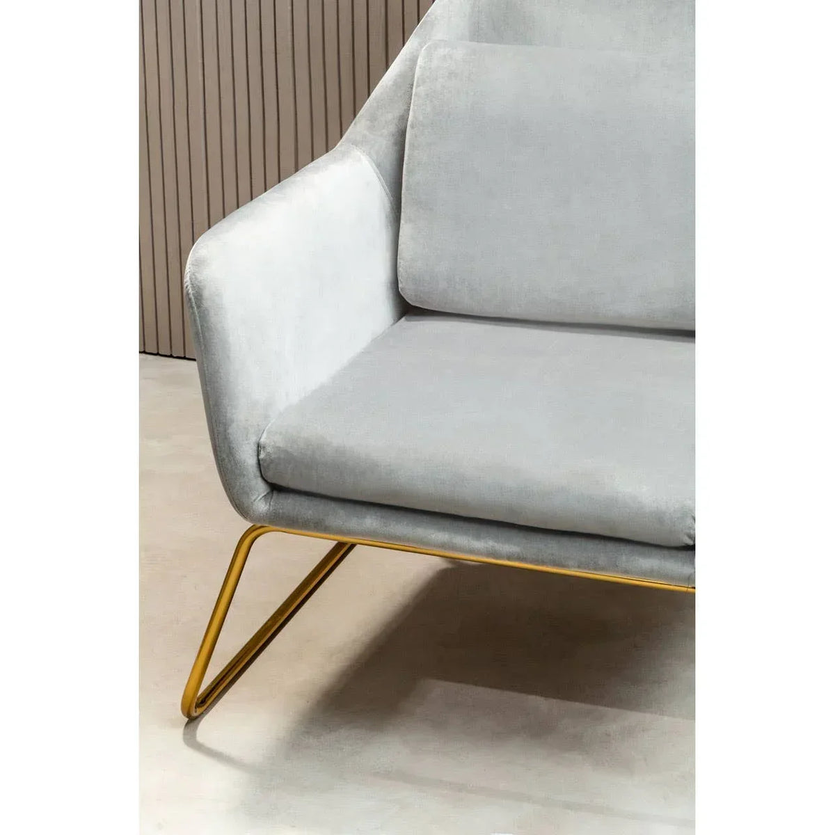 Light grey velvet armchair with gold metal legs, partial side view