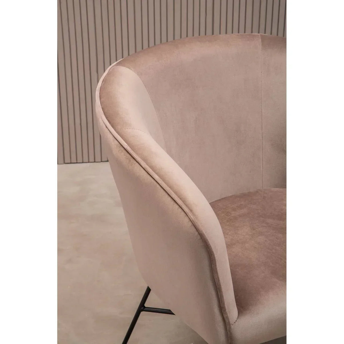 Taupe velvet accent chair with curved backrest and black metal legs on neutral floor
