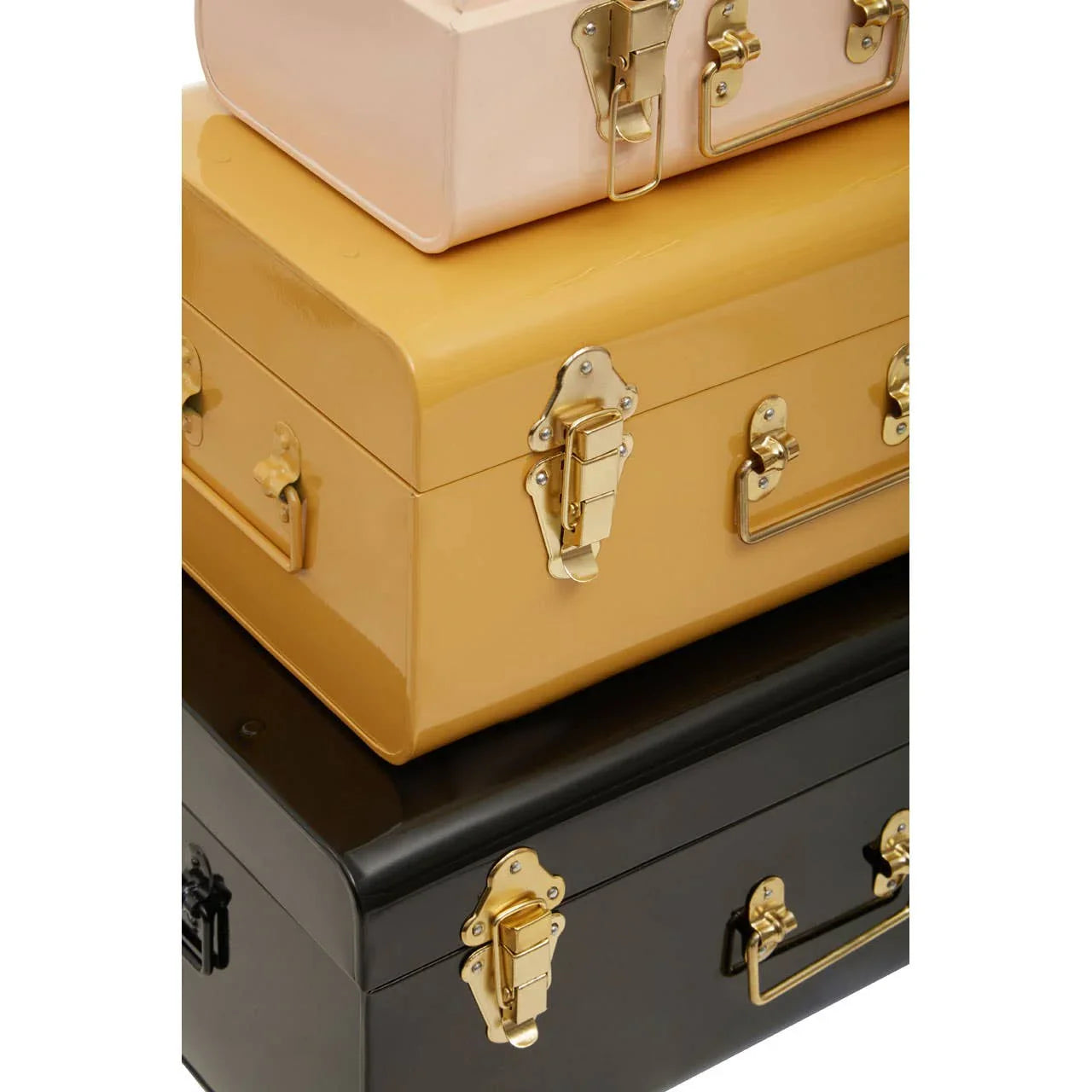 Stacked metal storage trunks in pink, gold, and black with gold latches and handles