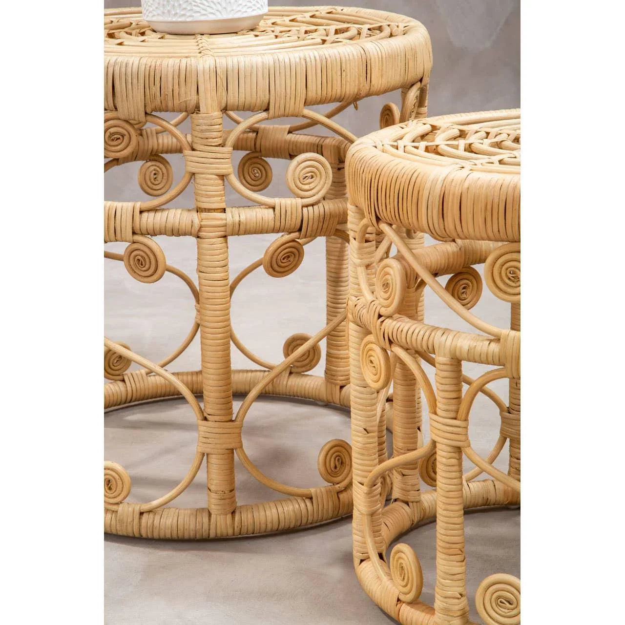 Round rattan side tables with swirl detail and natural finish on neutral background