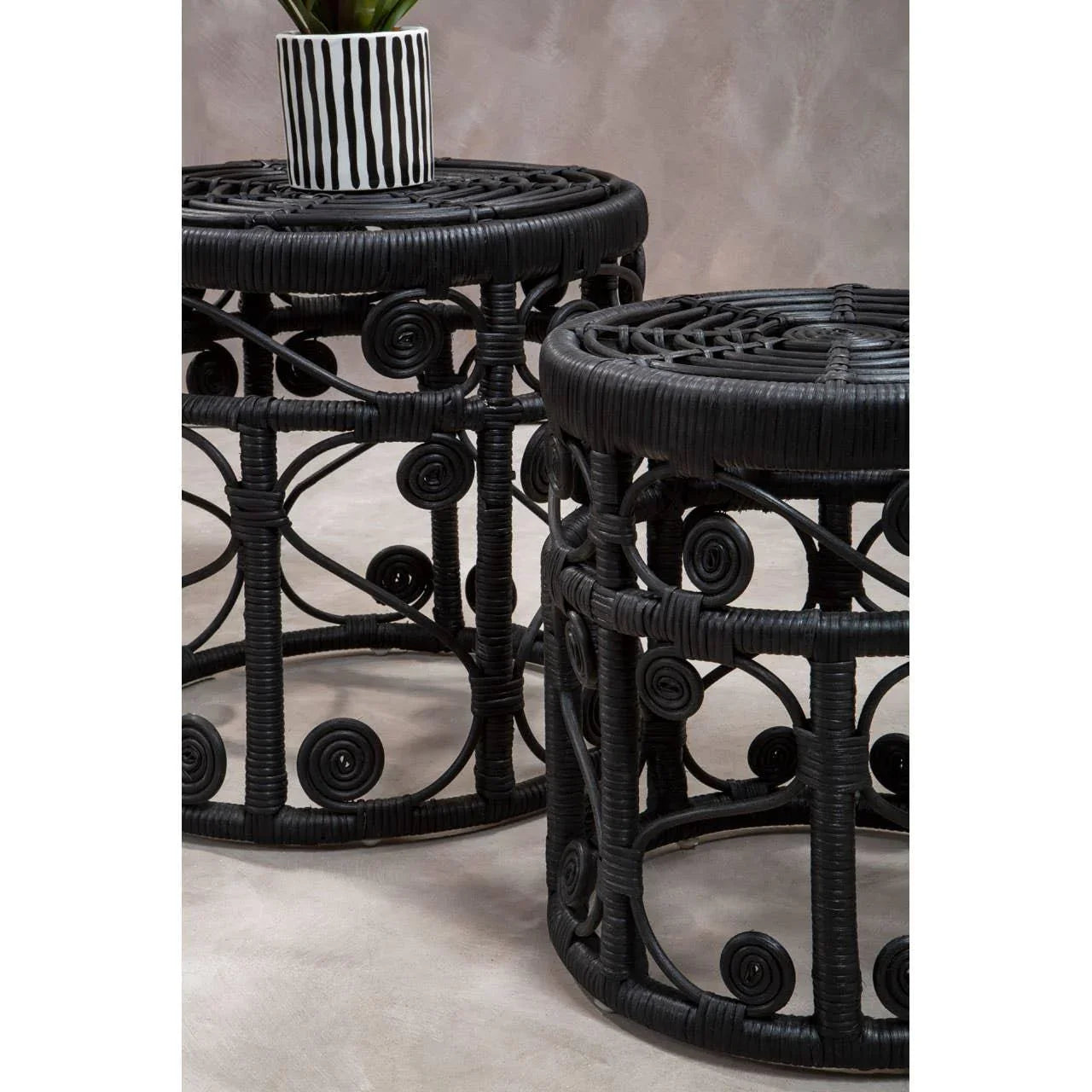 Pair of round black rattan side tables with spiral detailing and decorative top surface