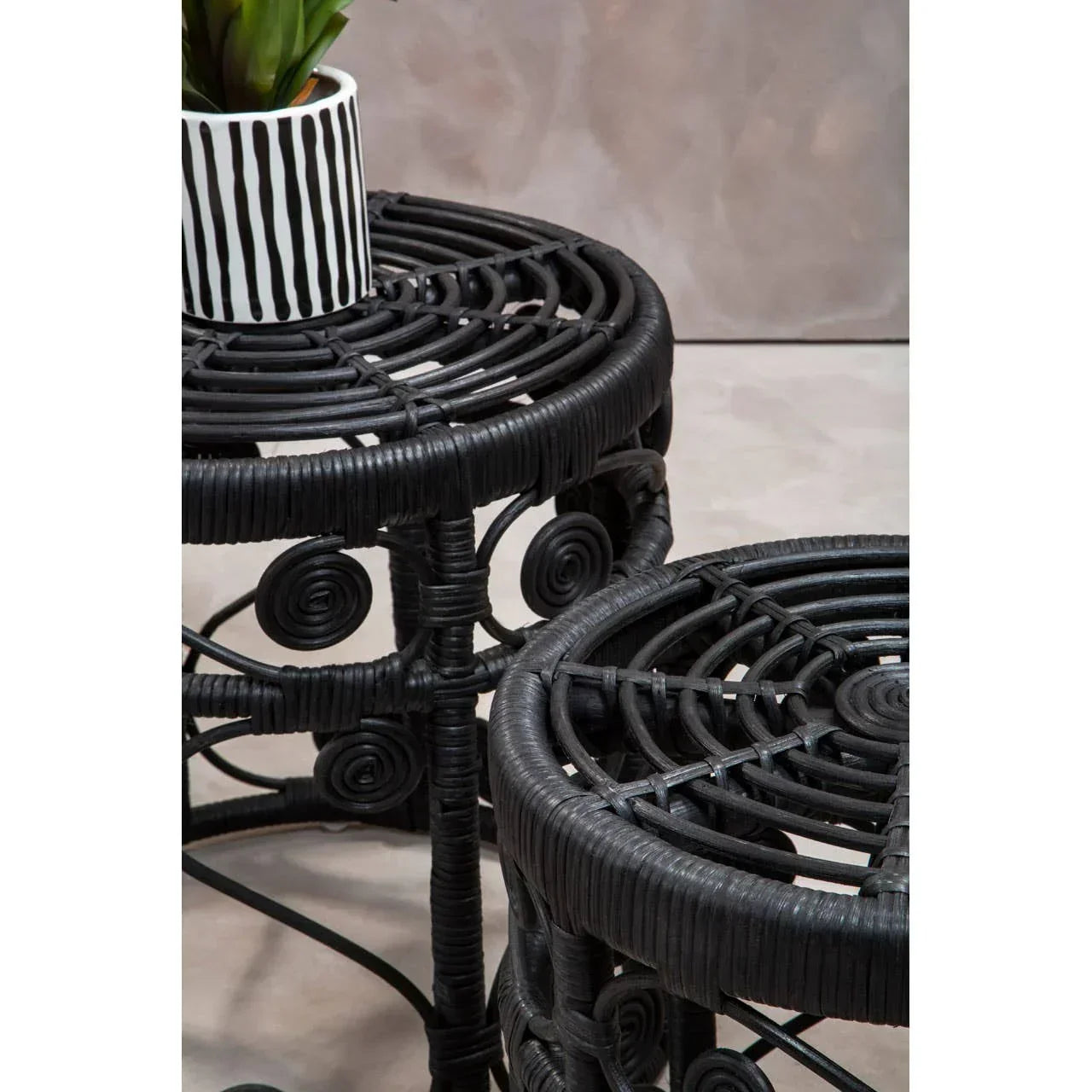 Black rattan side tables with spiral detail and decorative plant pot on top