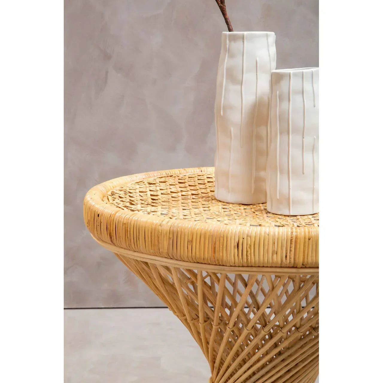 Round rattan side table with woven base and two white ceramic vases on top