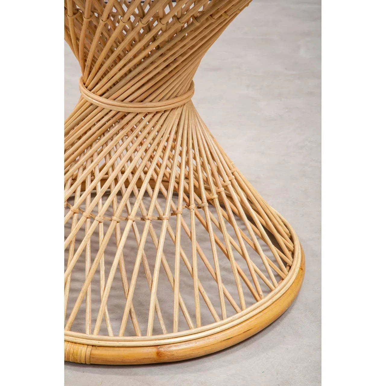 Natural rattan dining table base with spiral woven pattern on concrete floor