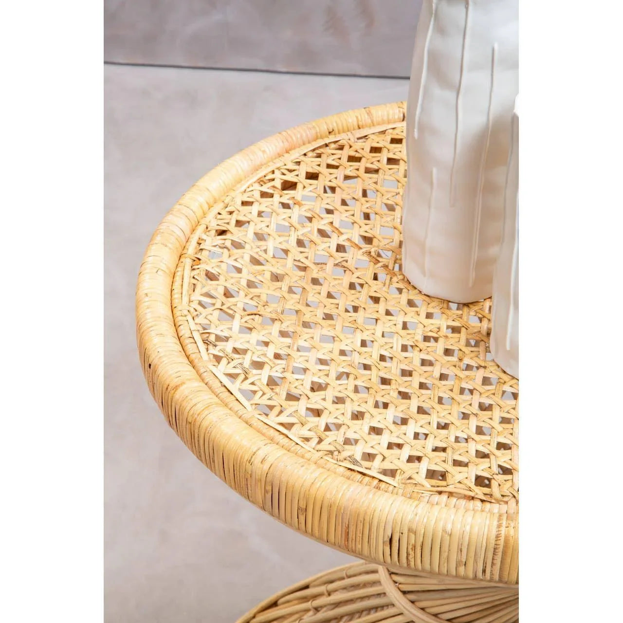 Round rattan side table with woven top and two white ceramic vases