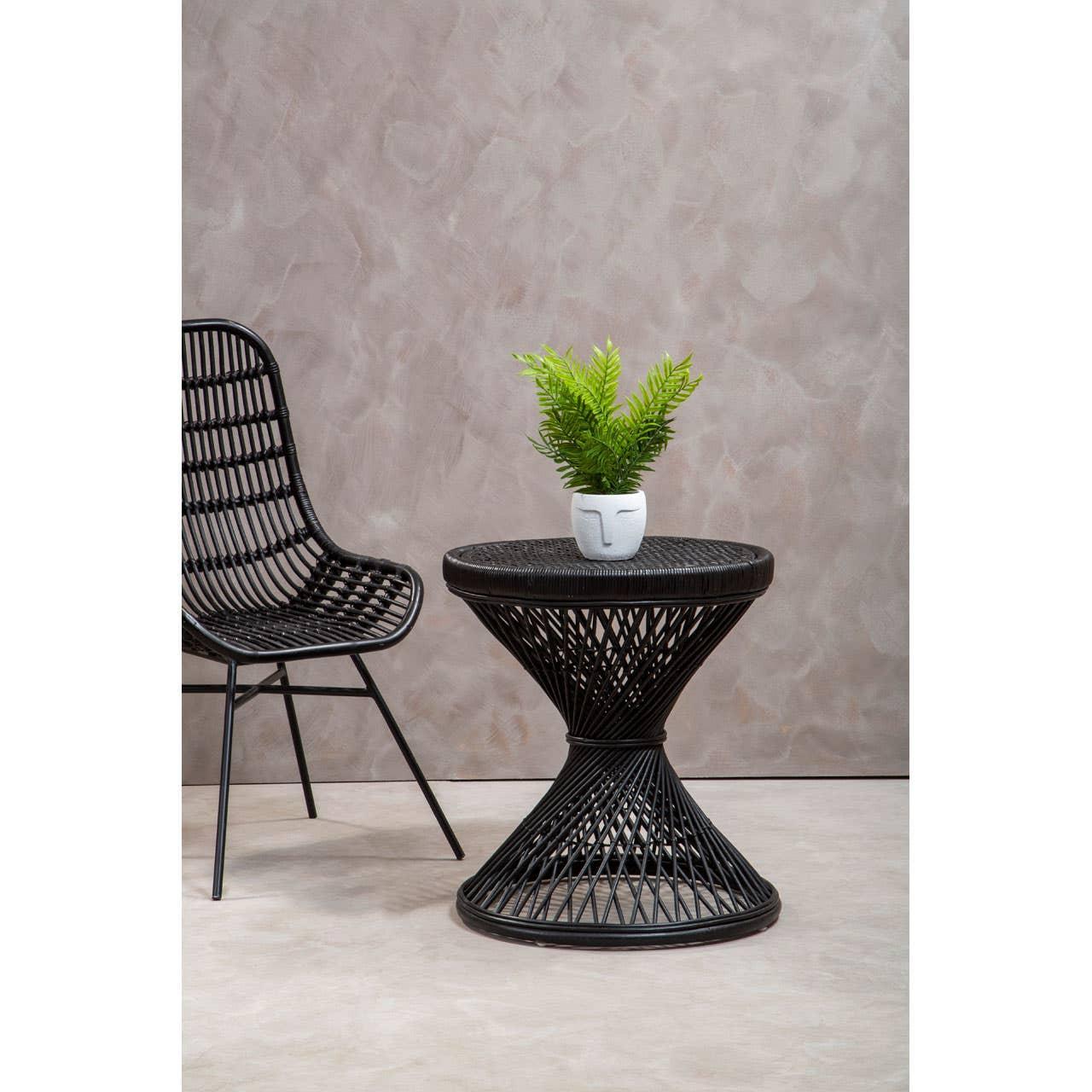 Black rattan accent chair and round wicker side table with plant in white vase