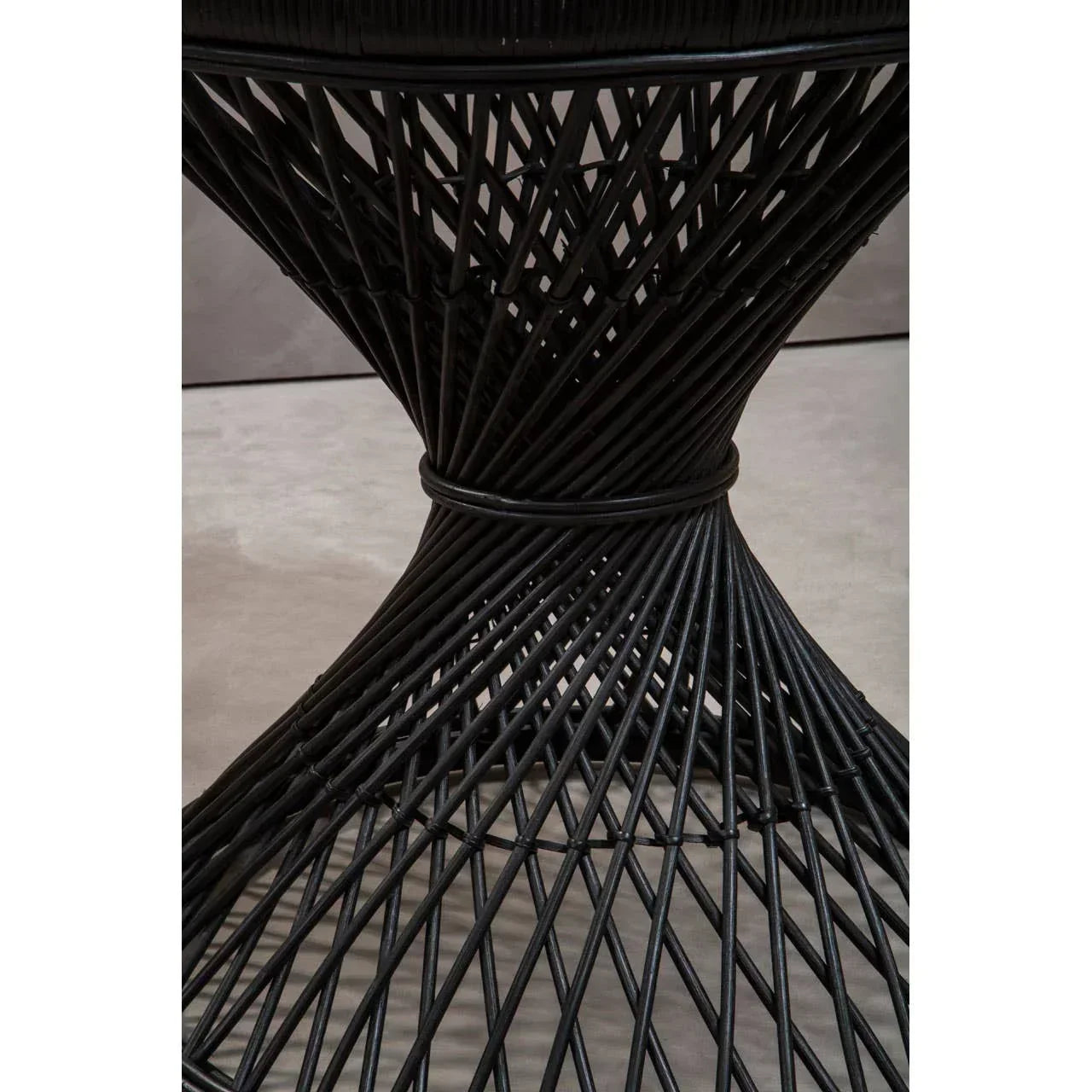 Black rattan dining table base with geometric crisscross pattern, close-up view
