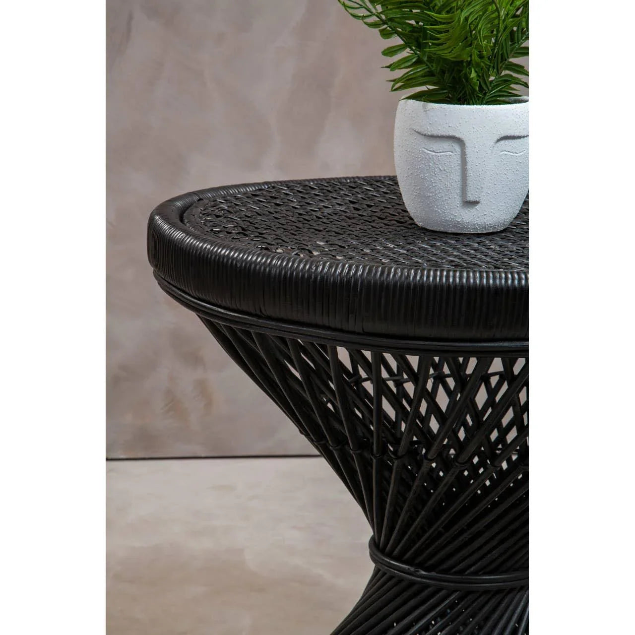 Black rattan side table with woven top and plant in white face planter