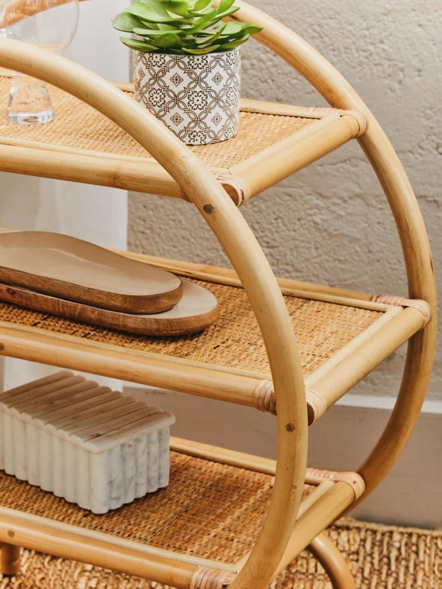 Three tier bamboo shelving unit with woven rattan shelves and decorative items