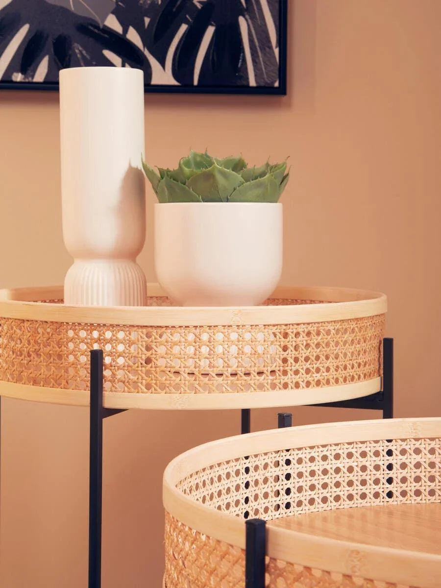 Woven rattan side table with black legs, white vase and small plant, modern interior decor