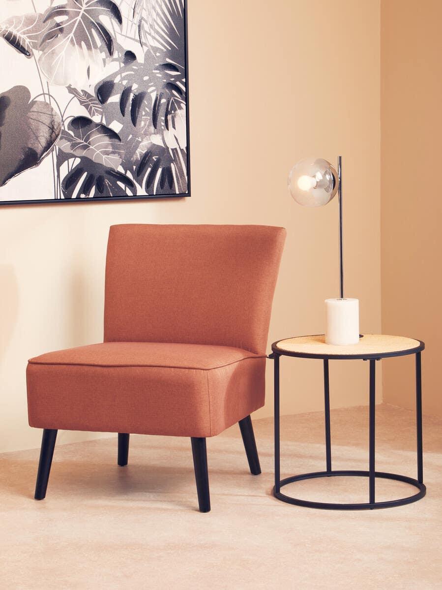 Brown accent chair with black legs beside round side table and modern lamp