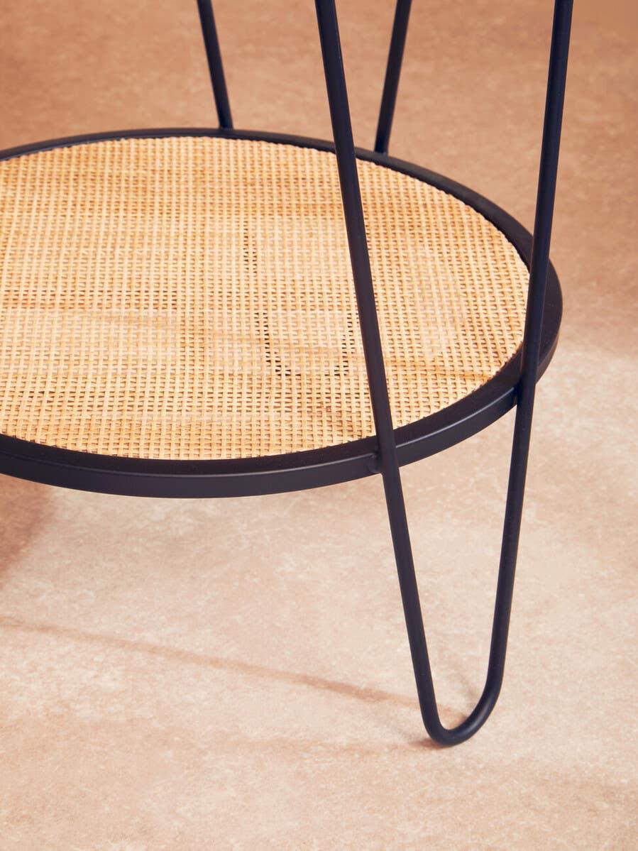 Round rattan side table shelf with black metal frame and hairpin legs on stone floor
