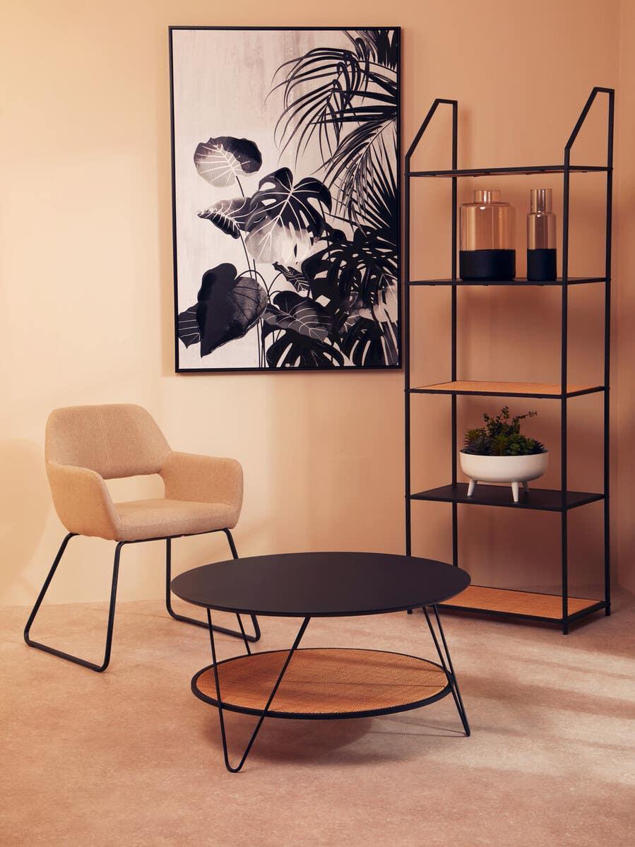 Modern beige accent chair with black metal base, round coffee table, shelving unit, wall art