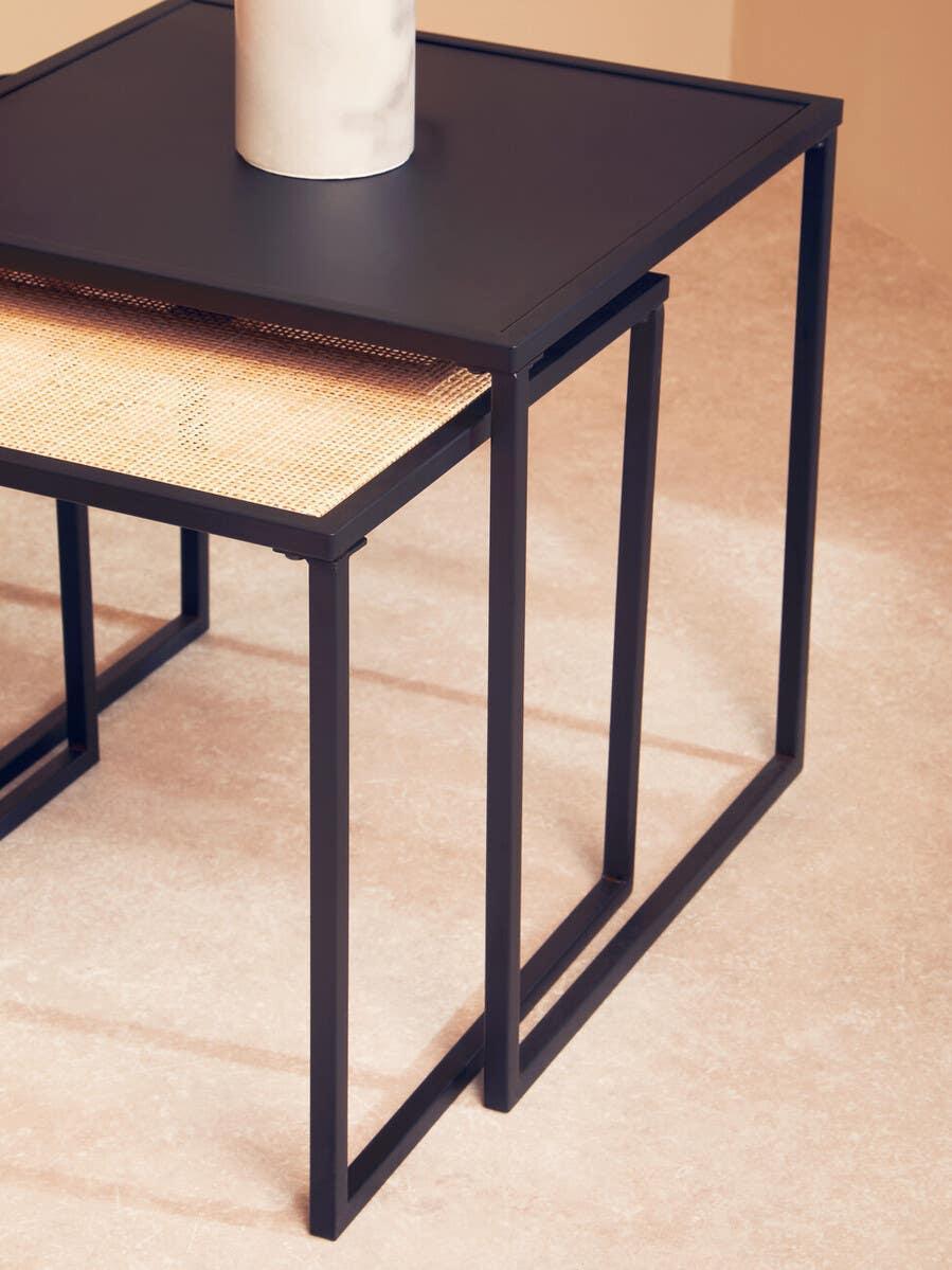 Black metal nesting tables with rattan shelf on beige tile floor