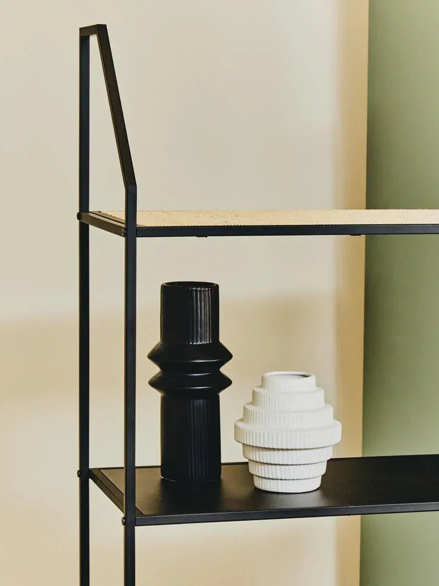 Black and white ceramic vases on modern black metal shelving unit against cream wall