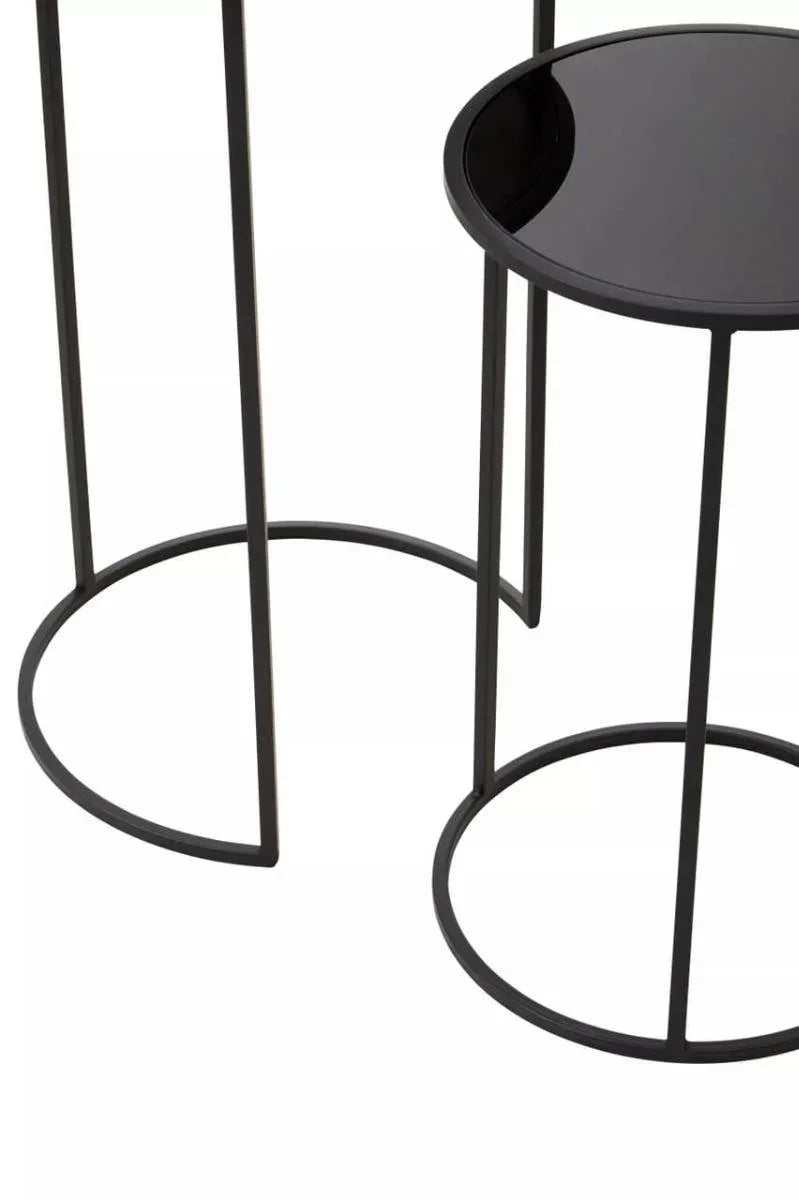 Black metal side tables with round glass tops and minimalist open frame bases