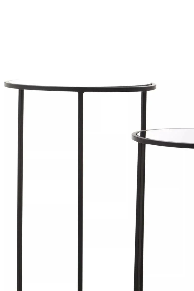 Black metal console table with slim legs and semi-circular glass top, close-up view