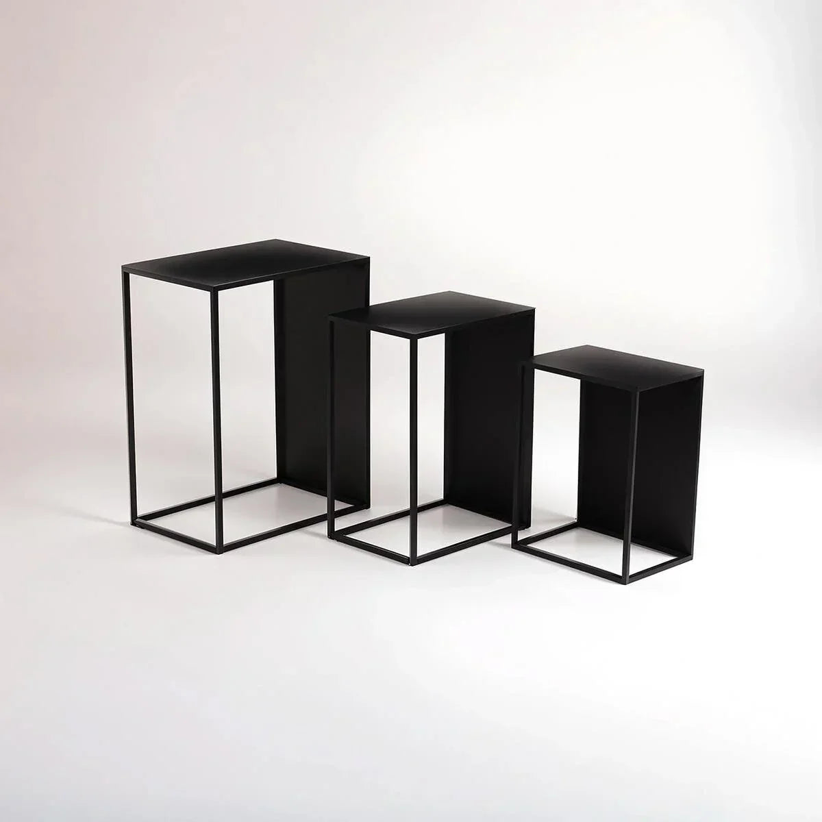 Set of three black metal nesting tables with minimalist open frame design on white background