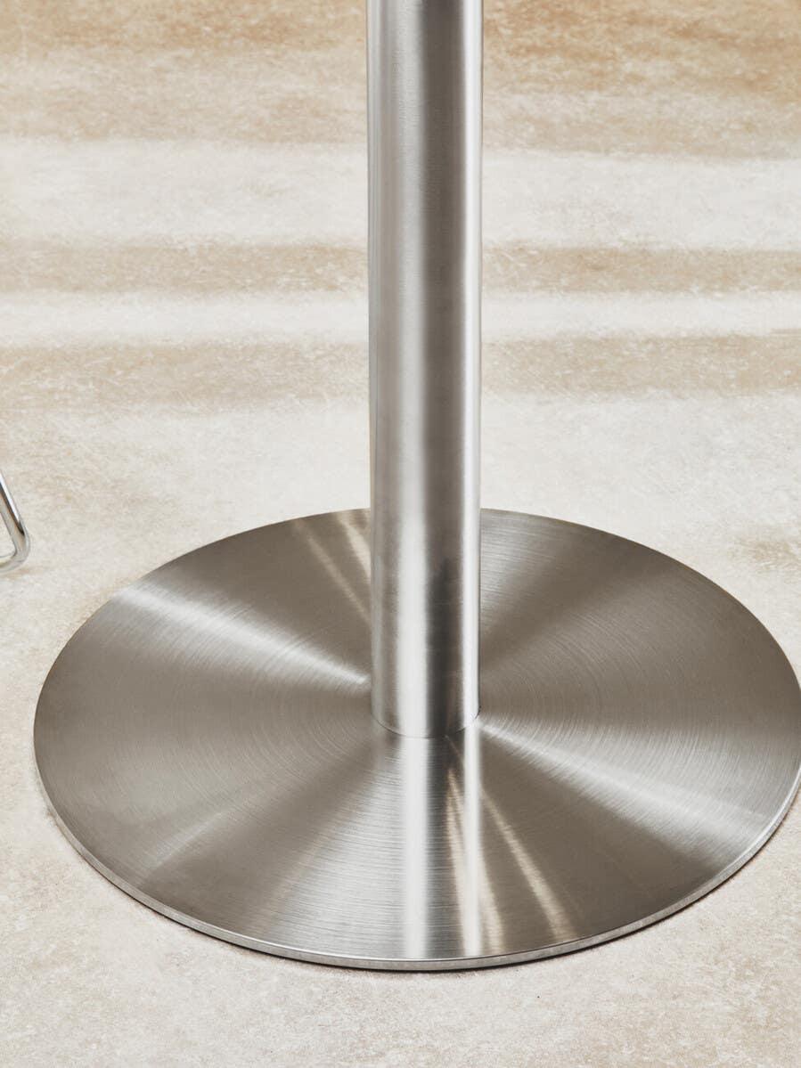 Brushed metal dining table base on light stone floor