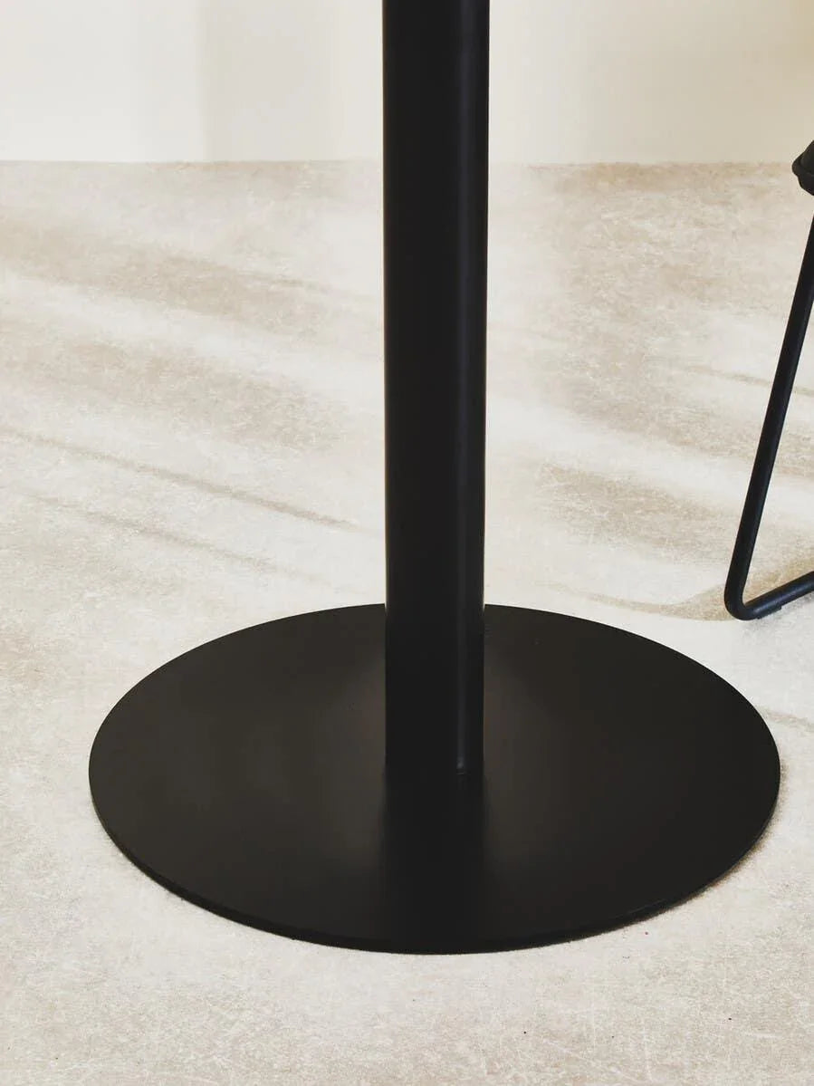 Black metal pedestal dining table base on light textured floor