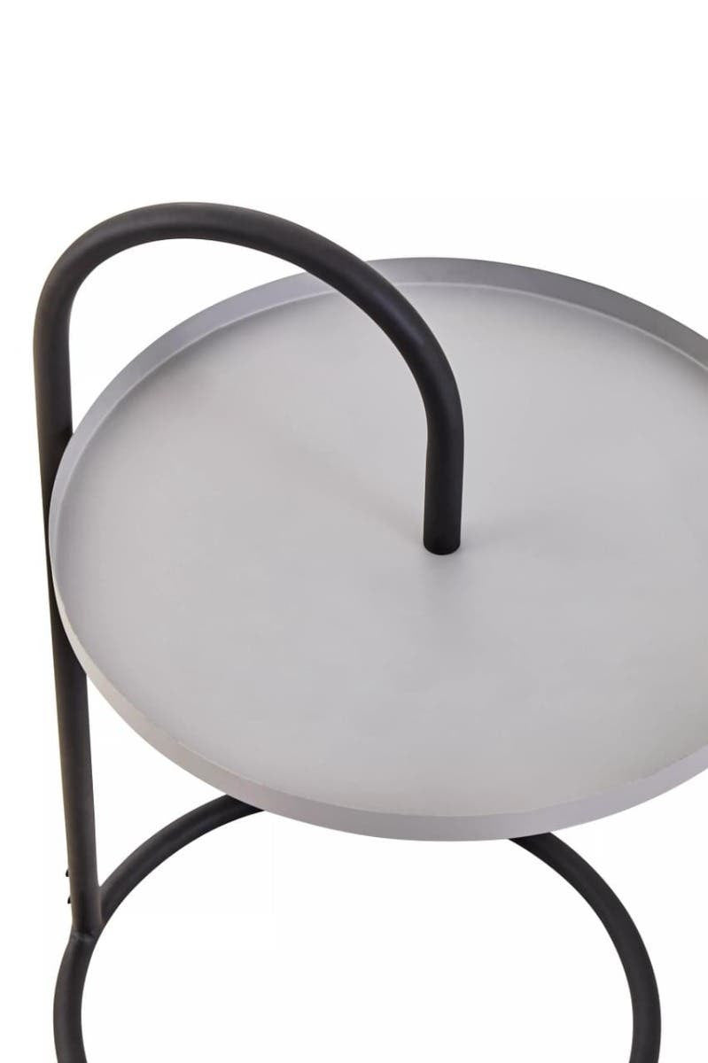 A modern side table featuring a round grey top with a smooth surface, supported by a sleek black metal frame. The table has a unique hanging design with a curved handle on one side, adding a contemporary touch to its overall aesthetic