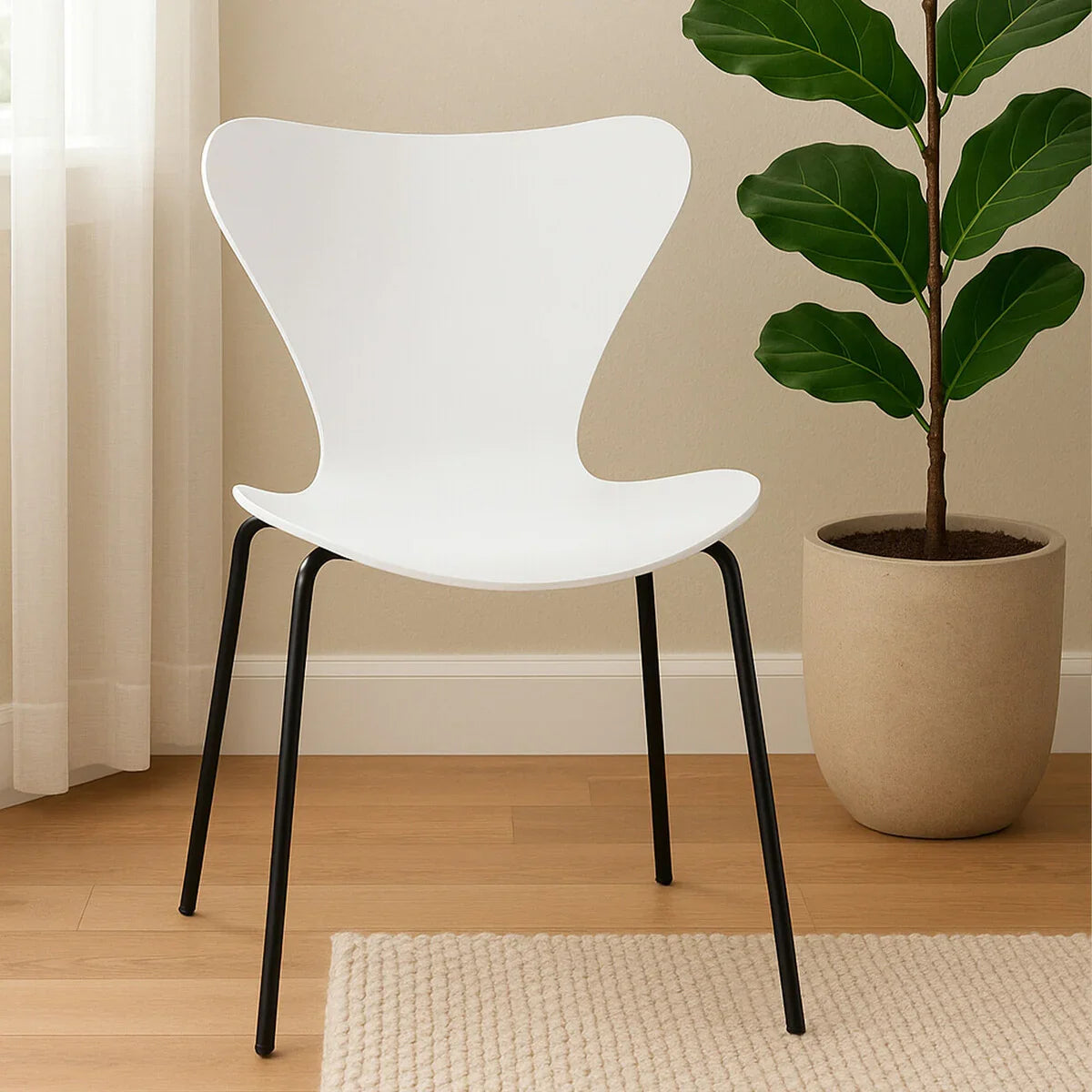 White modern dining chair with black metal legs on wooden floor beside potted plant