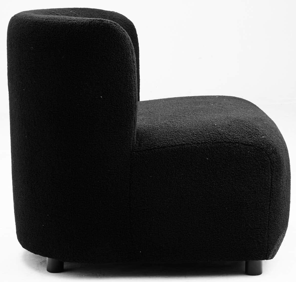 Side view of black boucle accent chair with curved back and low legs on white background