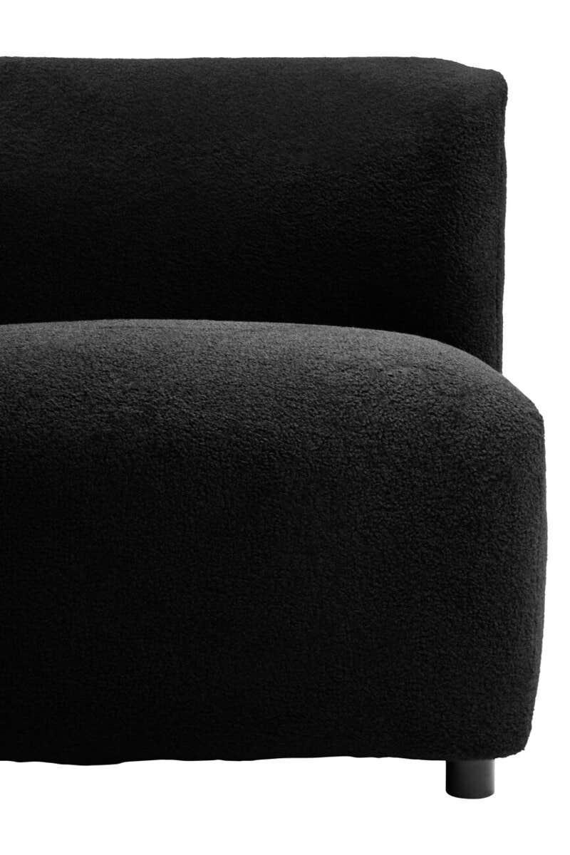 Close-up of black textured fabric sofa with curved arm and low round leg