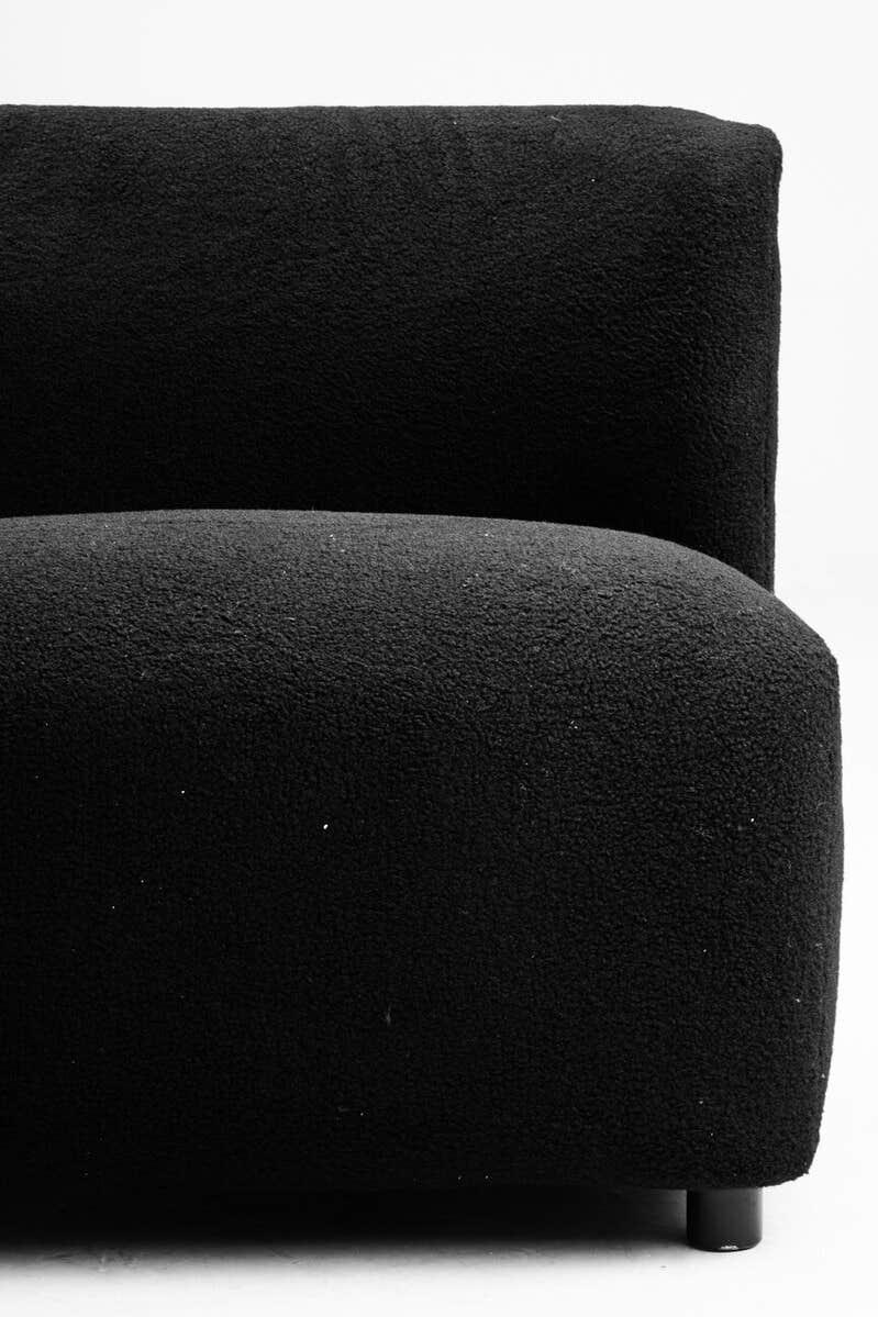 Close-up of black textured fabric sofa arm and seat with rounded edges