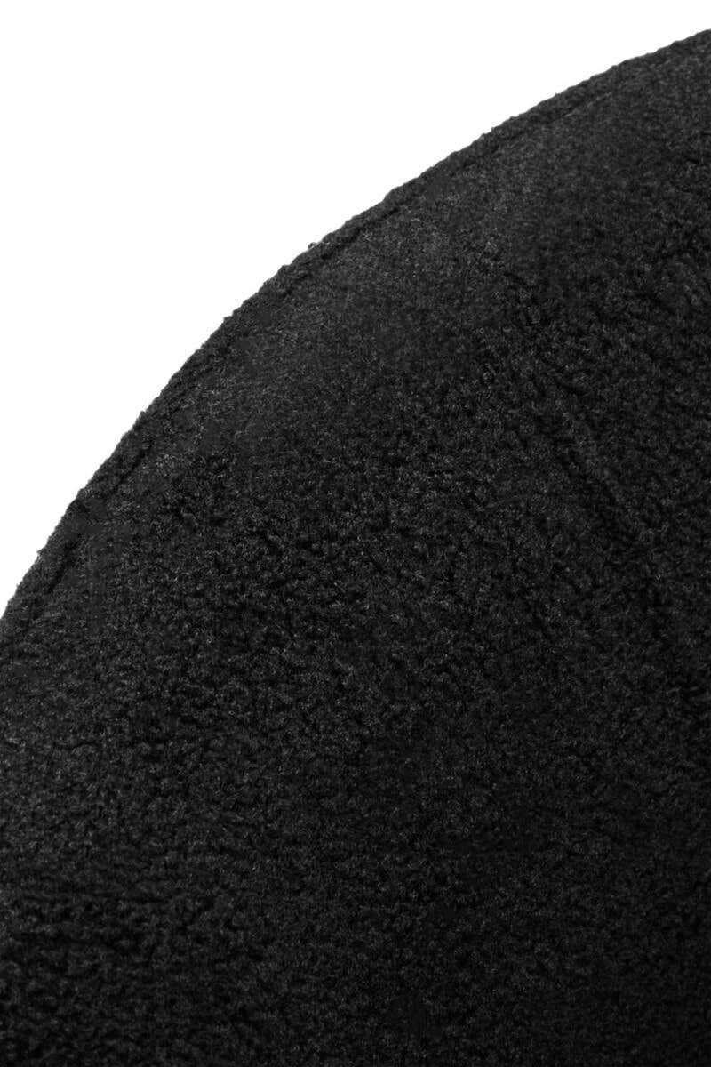 Closeup of textured black fabric upholstery on curved furniture armrest