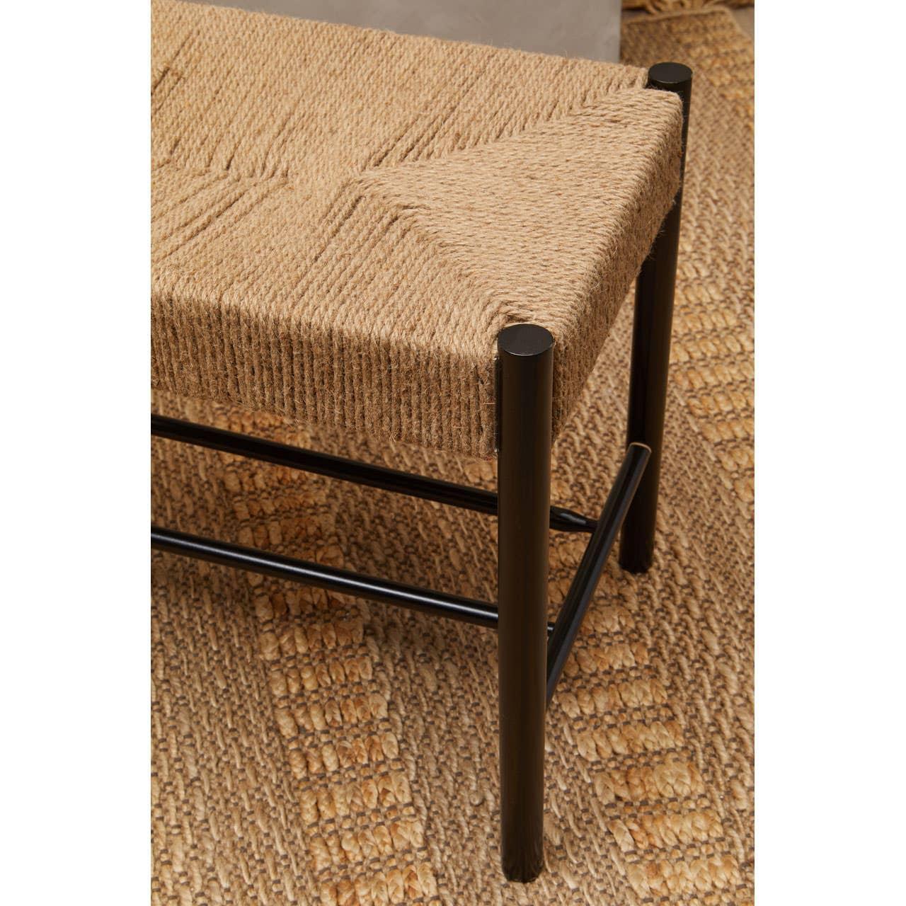 Woven seat bench with black metal legs on textured jute rug