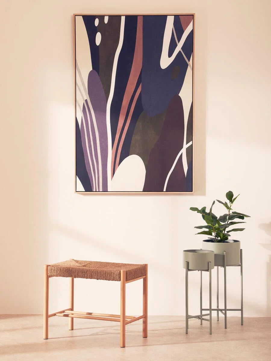 Woven seat wooden bench beside metal plant stands with greenery in a modern hallway