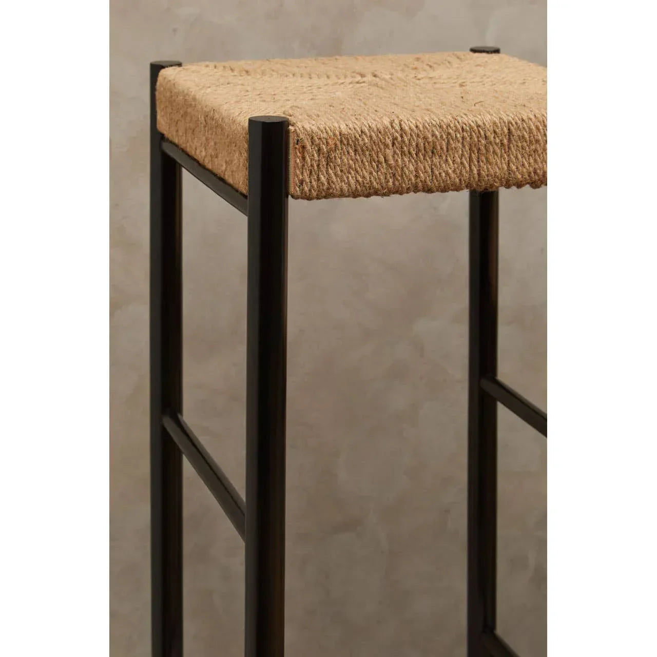 Closeup of bar stool with black metal frame and woven natural fibre seat