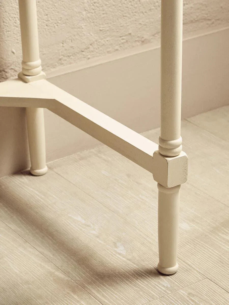 Cream painted wooden table legs with turned detailing on light wood flooring