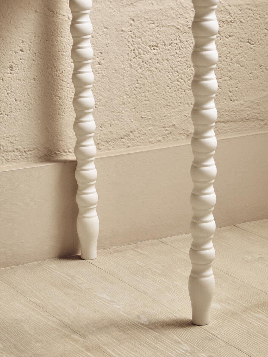 White wooden furniture legs with spiral carving on a light oak floor