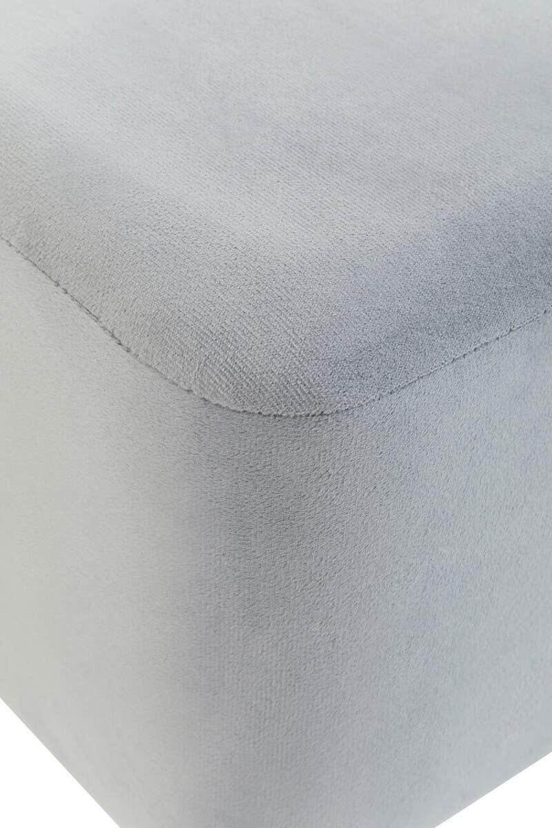 Square stool upholstered in soft grey velvet, featuring clean lines and a smooth surface. The edges are slightly rounded, and the fabric has a subtle sheen, adding a touch of elegance