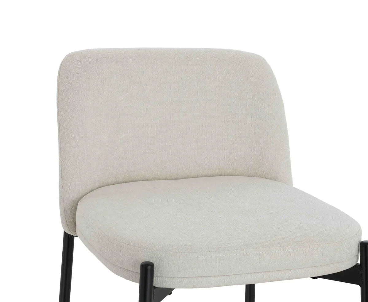 Cream upholstered dining chair with black metal legs, close view of seat and backrest