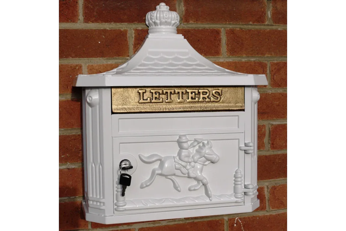 White cast iron post box with gold letter slot, horse design, wall mounted on brick exterior