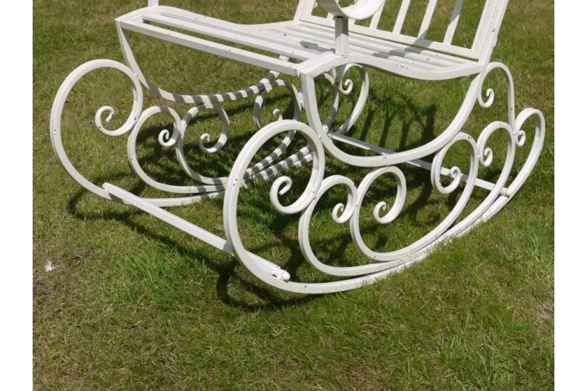 white metal garden rocking bench with ornate scroll design on grass
