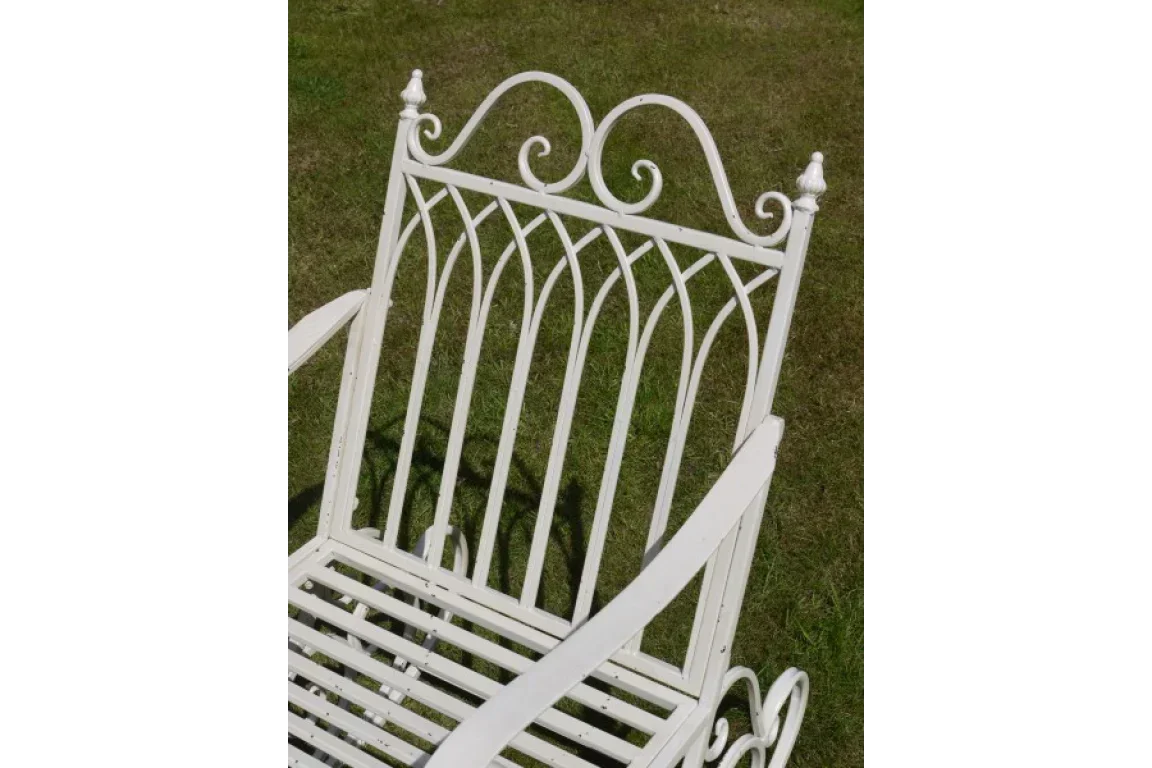 White metal garden bench with decorative scrollwork on grass