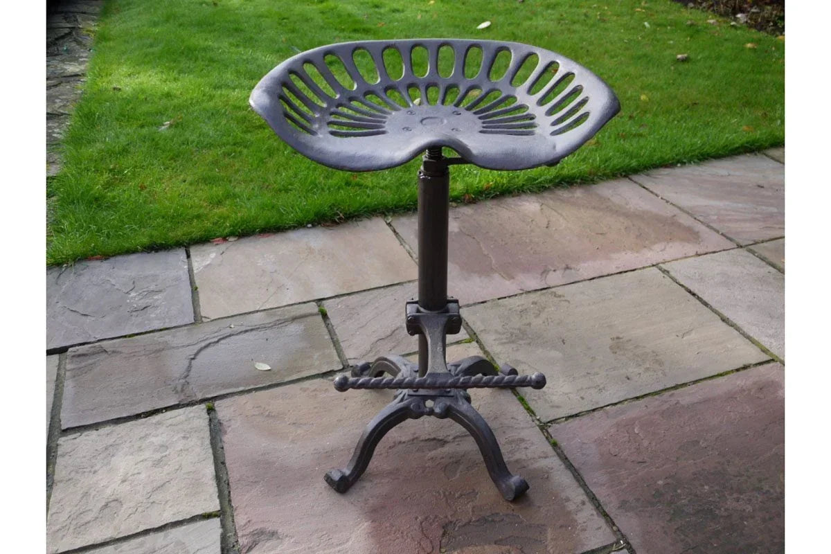 Cast iron tractor seat bar stool with footrest on stone patio
