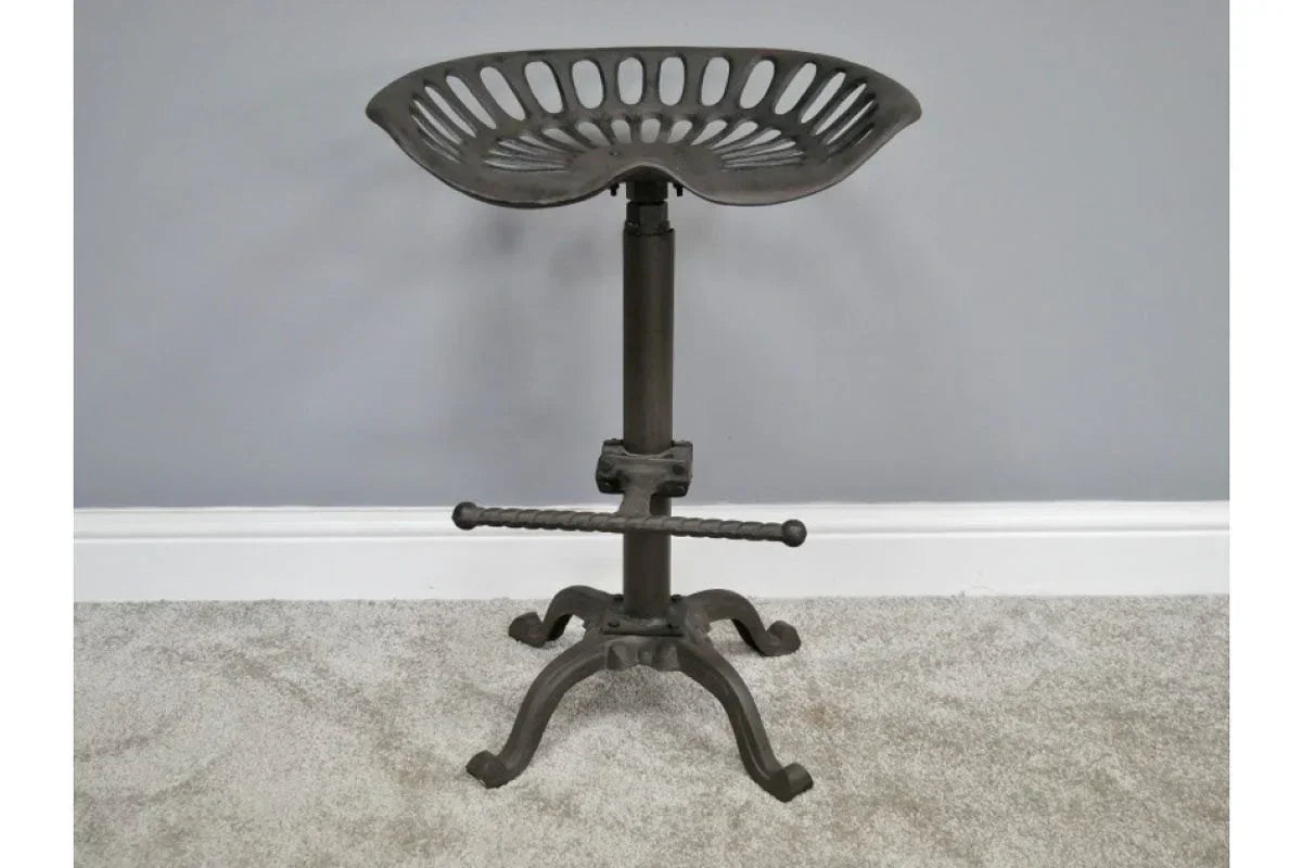 Industrial metal bar stool with tractor style seat and footrest on grey carpet