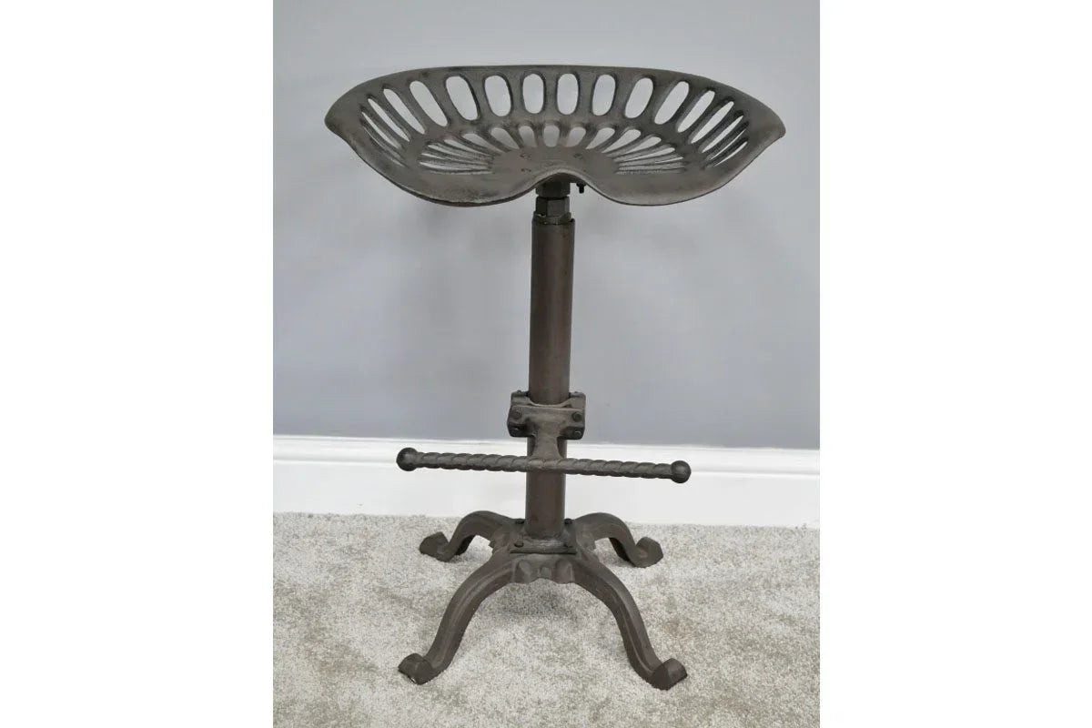 Industrial metal tractor bar stool with footrest and curved seat on carpeted floor