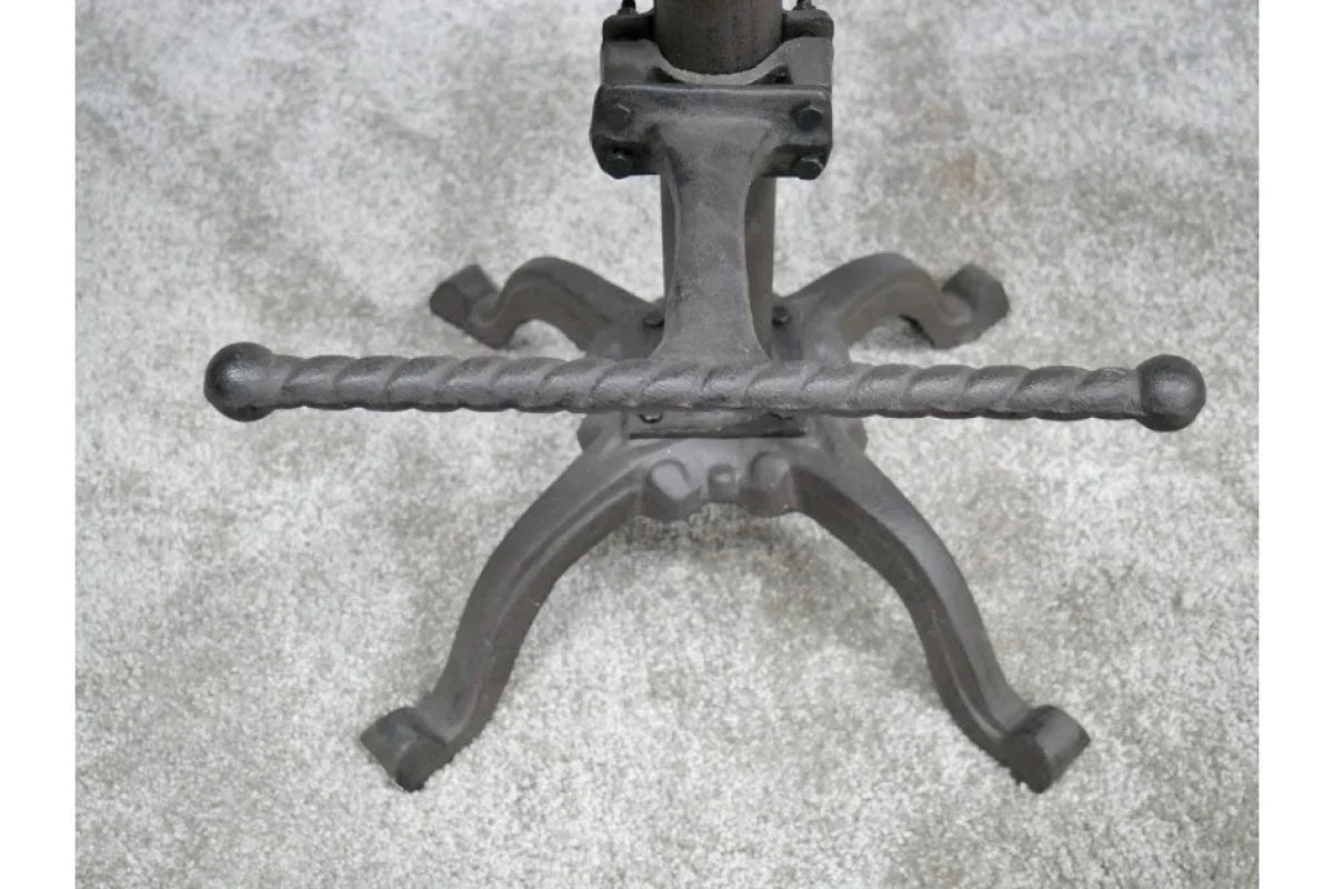 Cast iron table base with twisted metal footrest on grey carpet